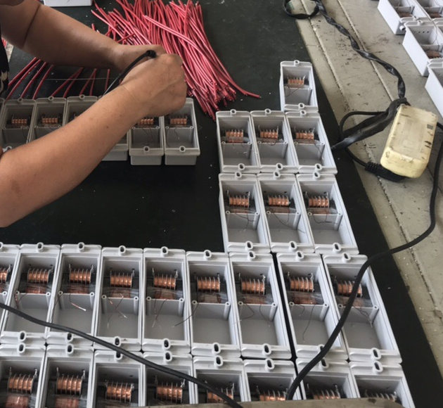 Hands assembling electrical components at a manufacturing partner